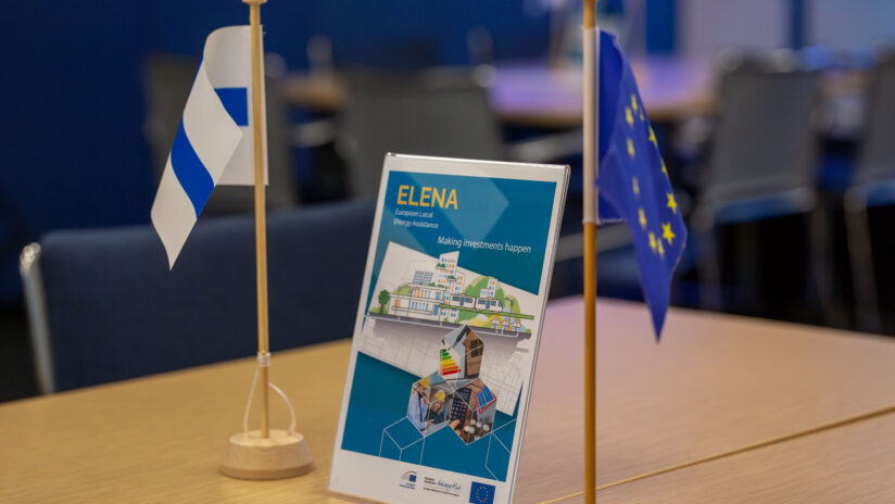 ELENA event table sign between the tiny flags of Finland and EU.